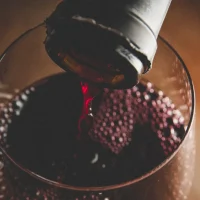 Wine glass being filled with red wine from a bottle