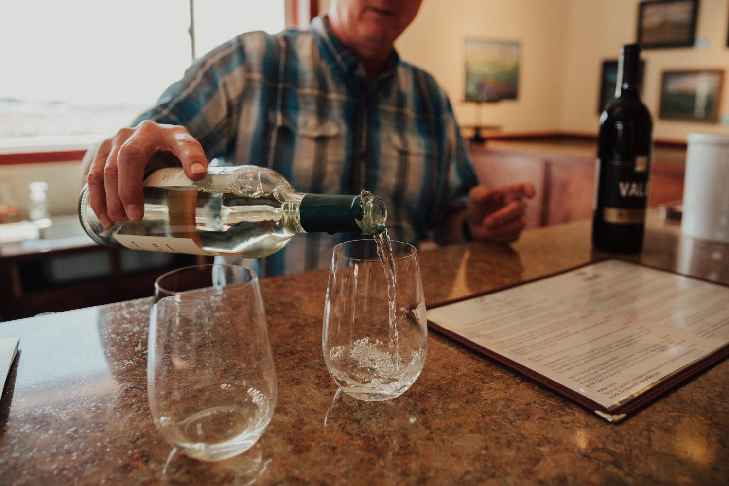 White wine being poured into a stemless wine glass in a tasting room