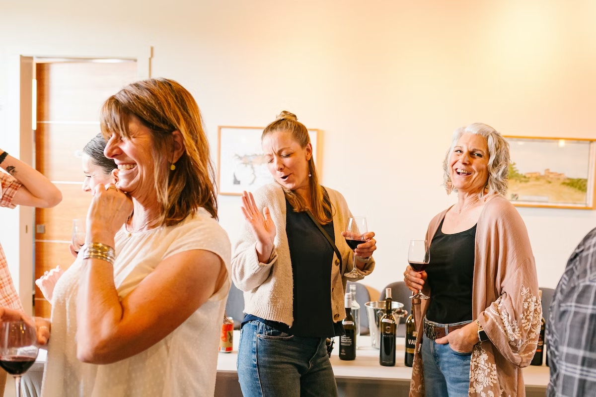 Four people laughing and drinking wine